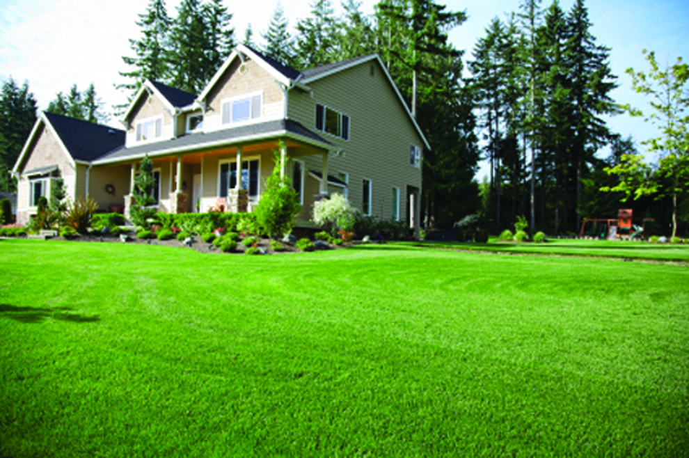 A tan house with freshly cut green grass.