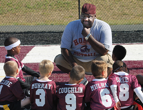 Dwight Vick talking with young football players