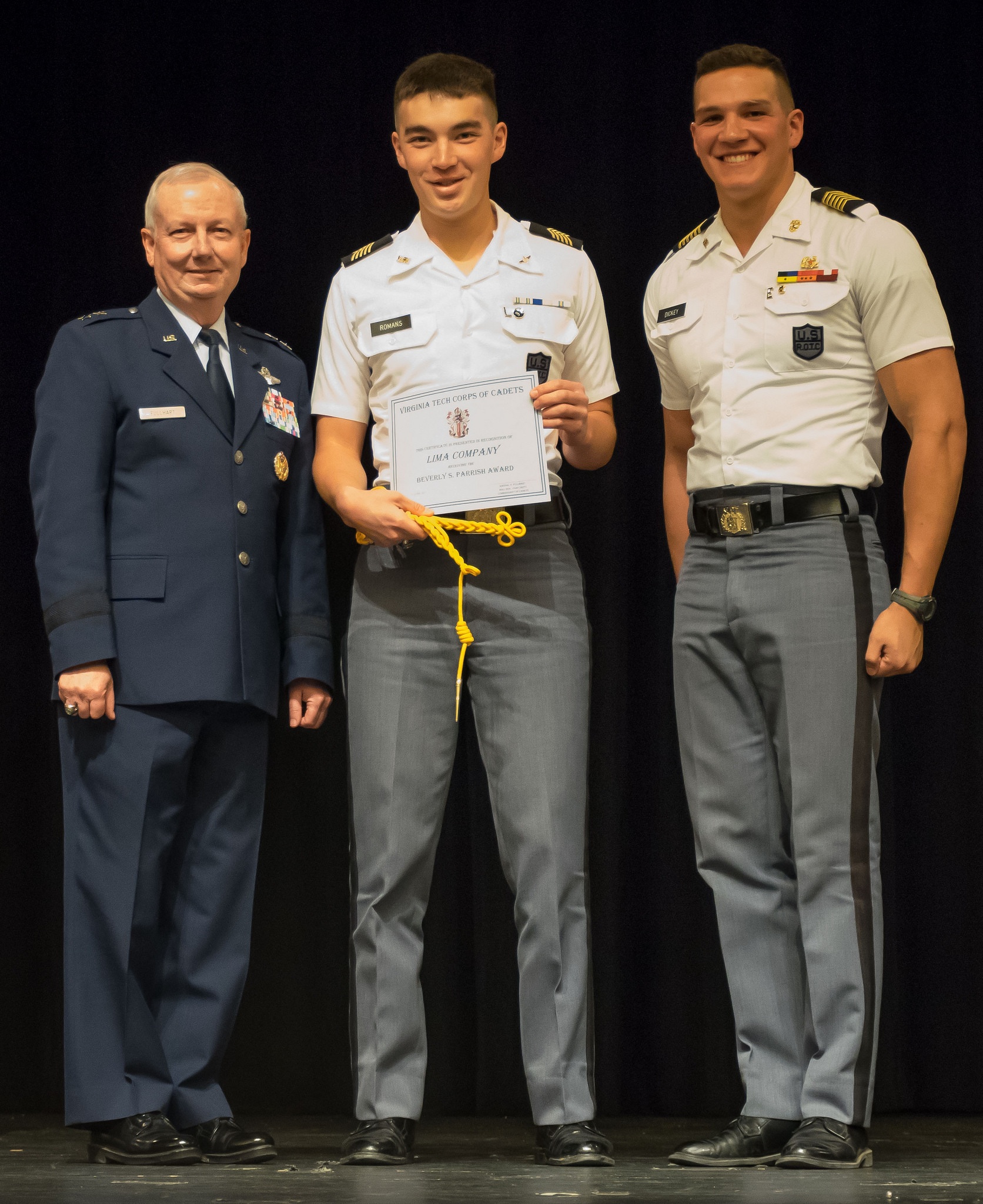 Cadet Stephen Romans (center) accepts the Gold Cord from the Commandant of Cadets Maj. Gen. Randal Fullhart (left) and the Regimental Commander Cadet Col. Austin Dickey (right) on the Burruss Hall auditorium stage.