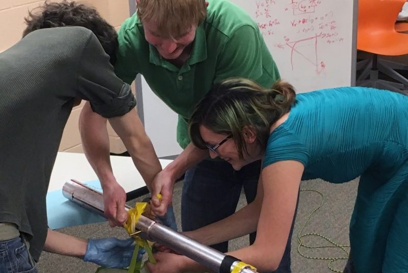 Virginia Tech first-year students (from left to right) Ben Beheydt, Mitchell Woodhouse, and Jackie Bertone test the weight capacity of their telescoping arm.