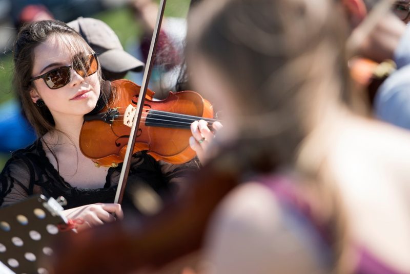 Unlikely Ensembles: Student playing violin outside