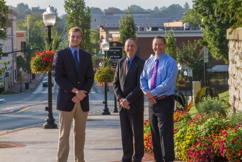 Student, town, and university representatives to the town-gown committee stand on Main Street at the entrance to Virginia Tech.