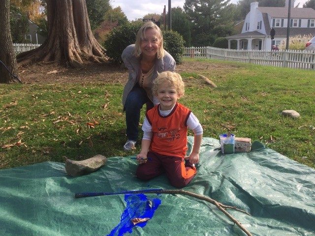 Child and his grandmother help paint branches blue for the Blued Trees project.