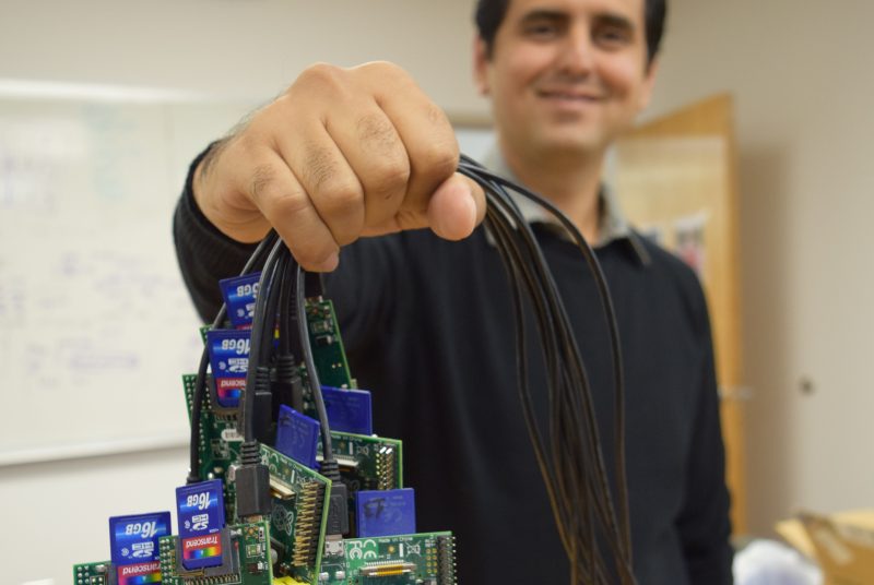 Man holds a group of mini computers by their connected wires.