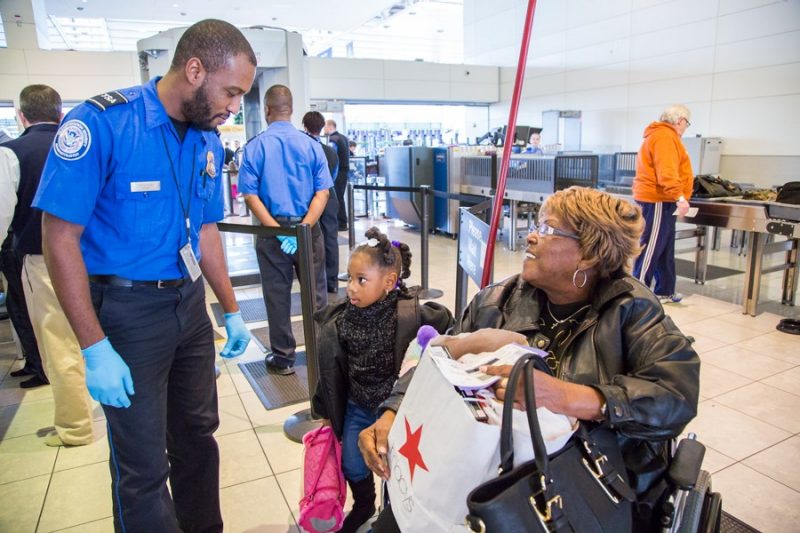 TSA officer talking to woman and child at airport