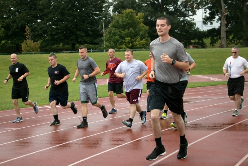 Ten members of the Virginia Tech Police Department run along a track in the rain.