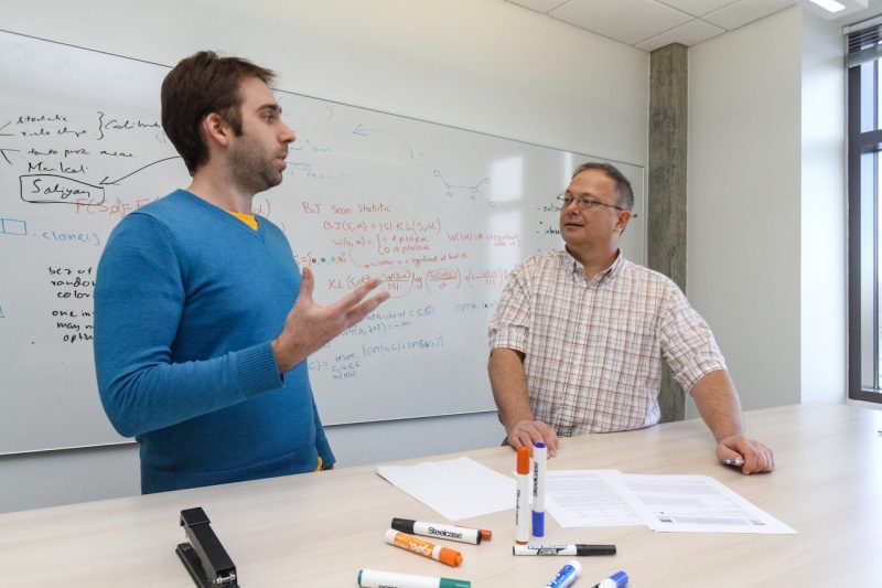 Brian Goode, left, and Chris Kuhlman, discuss their research in front of a white board.