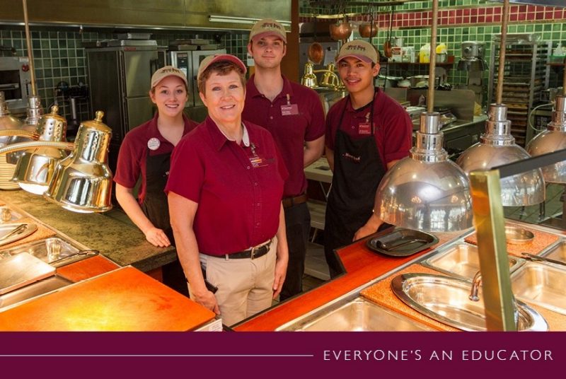 Debra Scanland poses behind the counter of JP's Chop House with a few student employees. 