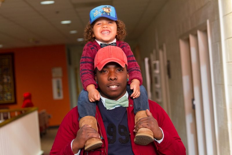 Gucci smiles with his three-year-old son Jaiden on his shoulder.