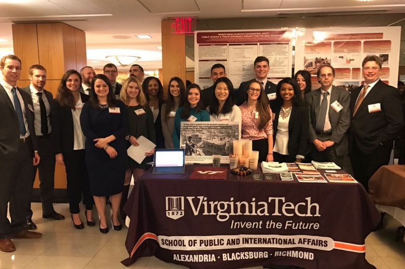 Students and faculty standing in back of  table with Virginia Tech signage during  U.S. Department of State Diplomacy Lab Fair.