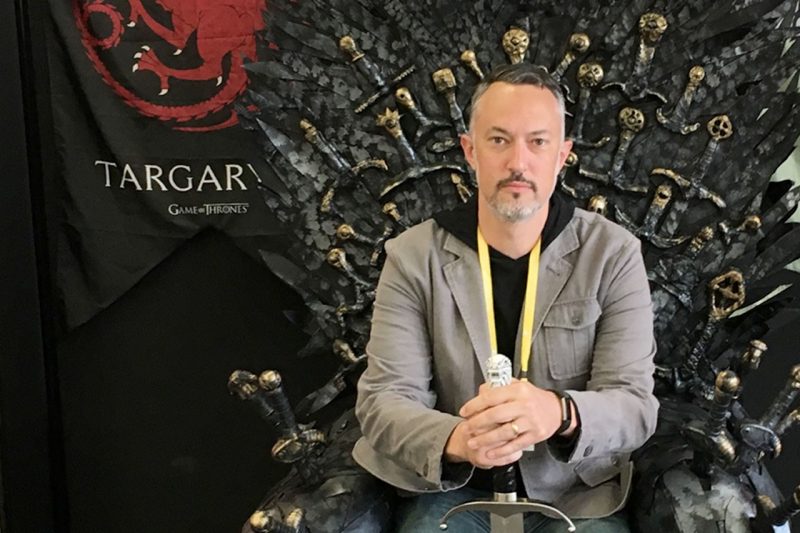 Matthew Gabriele sitting on Iron Throne replica from Game of Thrones