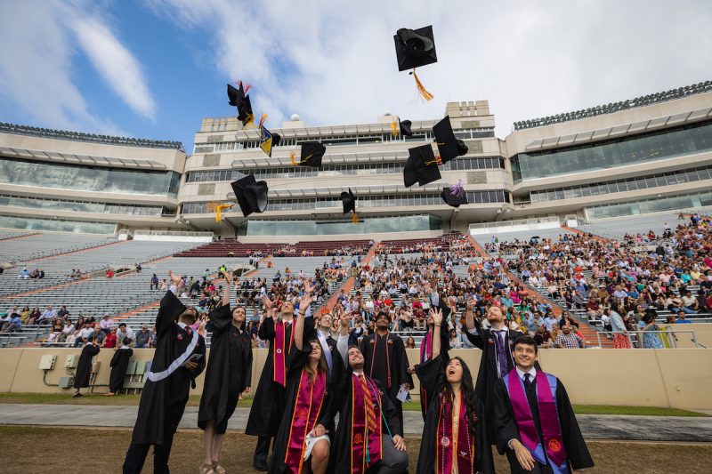Hokie grads throw their graduation caps into the air on Worsham Field. 