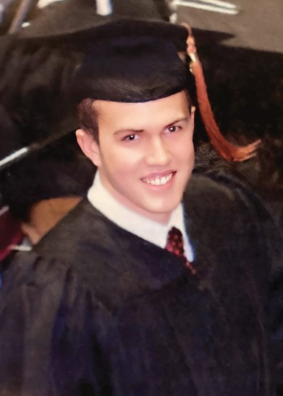 Joe Movic wearing a cap and gown during commencement