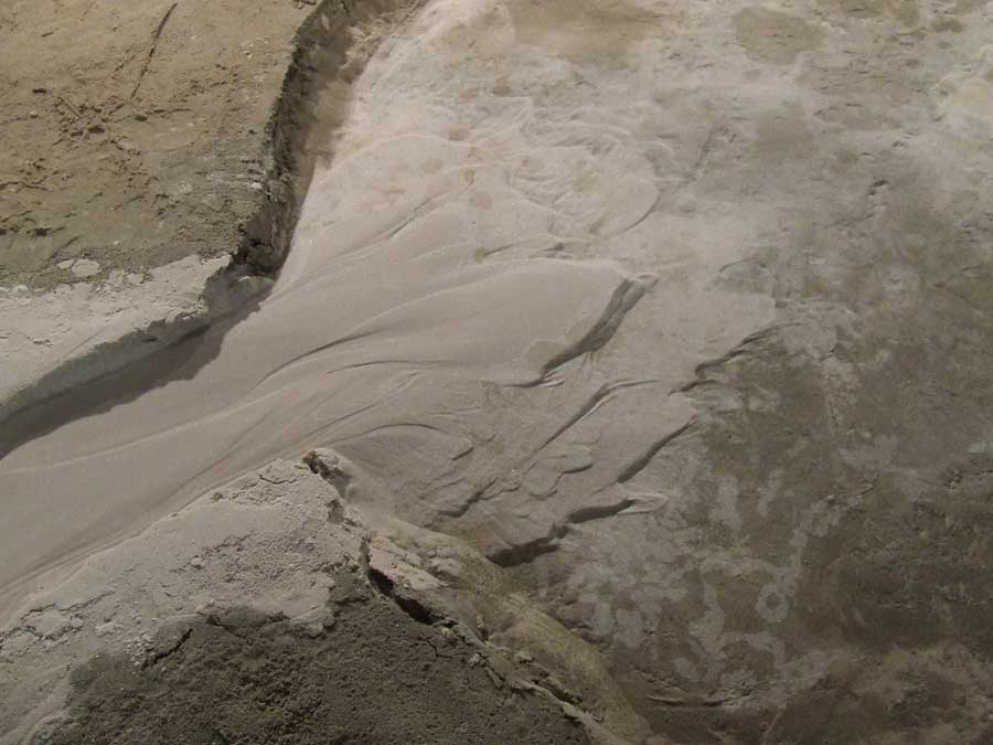 A delta (~40 cm across) with steps (about 2 cm in the highest places) draped over a mock crater formed in the Eurotank at Utrecht University. The unusual 'stair step' shape is due to the fan depositing at the same time as the water level rises. Then the water flow into the channel is stopped and the water in the crater is allowed to drain by seeping into the floor. The photo was taken by Erin Kraal.