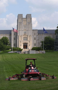 An employee mows the lawn in front of Burruss Hall.