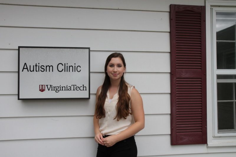 Zoe Waddell in front of the Autism Clinic sign