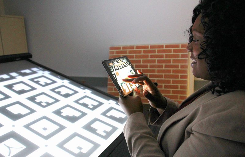 Student uses tablet computer to connect with tabletop display unit used for augmented reality research.