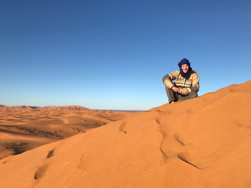 Andrew Knight sits atop a sand dune in the Sahara Desert. 