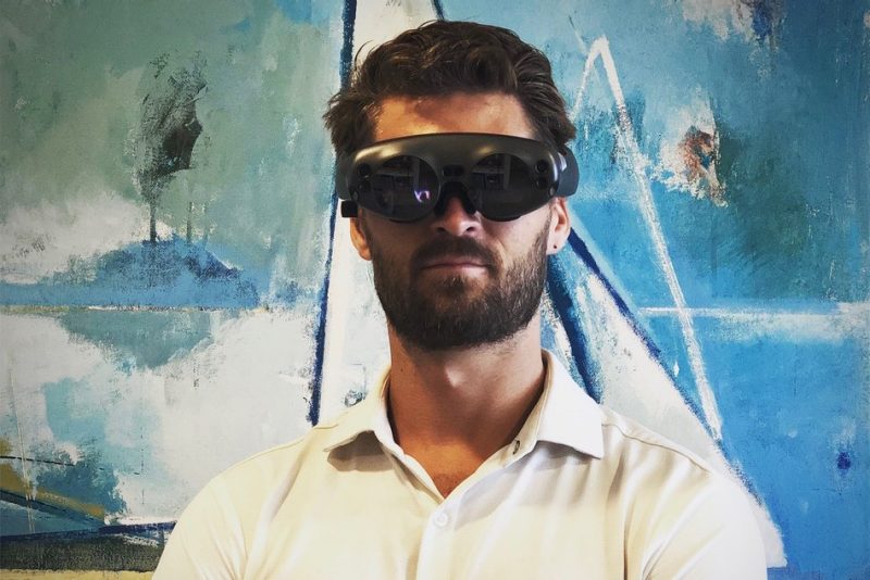 David Gull stands in front of a piece of art wearing a virtual reality headset