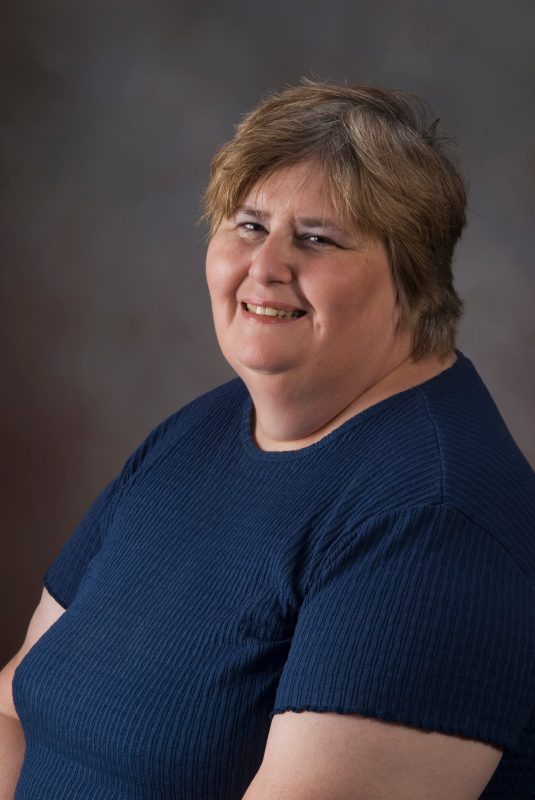 Cindy Koziol of the Department of Psychology poses in a blue shirt for a 2013 photo