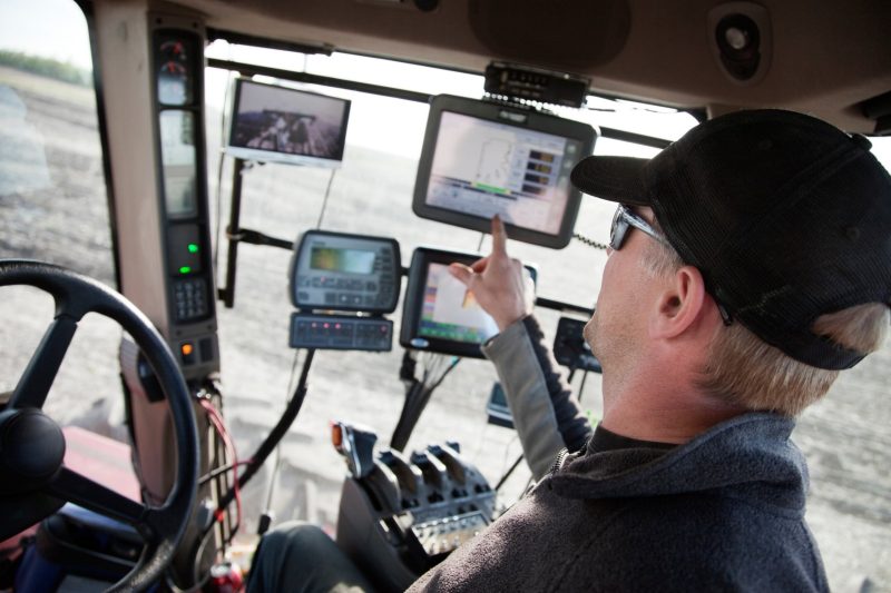 A farmer in a tractor using computer equipment.