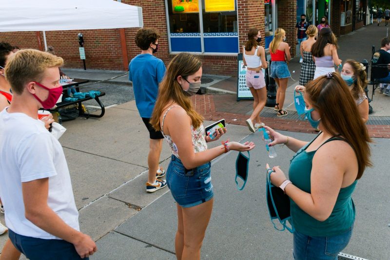 Students pass out hand sanitizer on College Avenue in downtown Blacksburg.