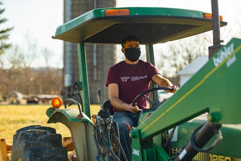 Shawn Jadrnicek is pictured driving a tractor with a field and silo behind him