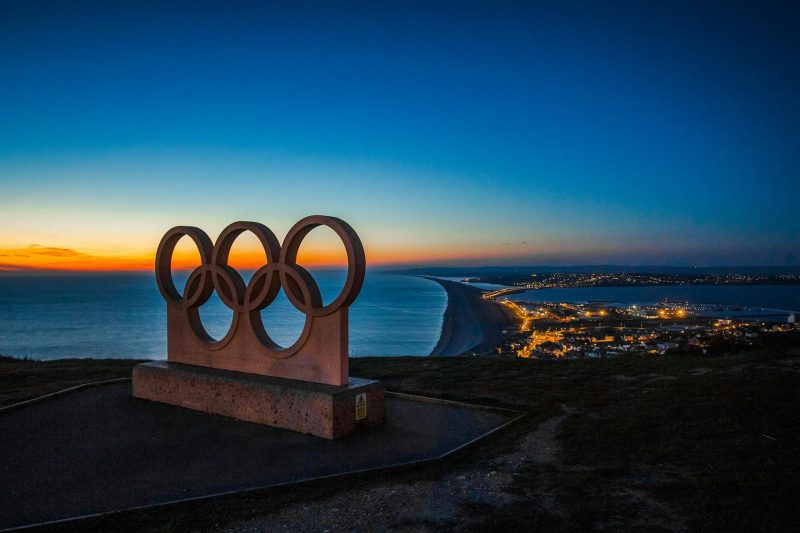 The Olympic rings at sunset on a hill. Courtesy Pixabay.
